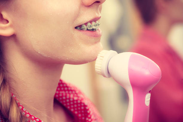 istock Woman using facial cleansing brush on face 683748070