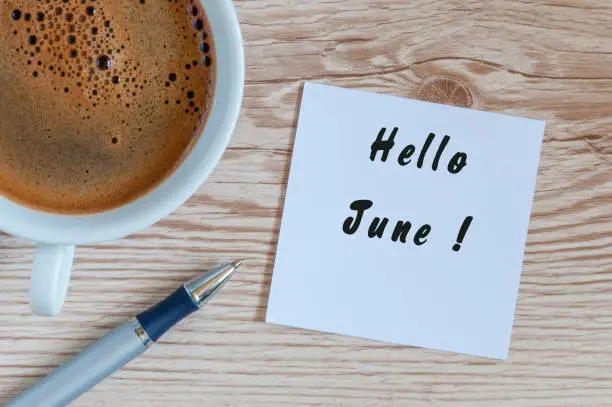 Hello June - message at home or office desk. With morning cup of coffee. Summer is Here concept.