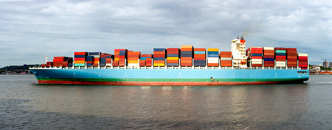 Manhattan skyline and World Trade Center in the background behind a container ship in New York Harbor