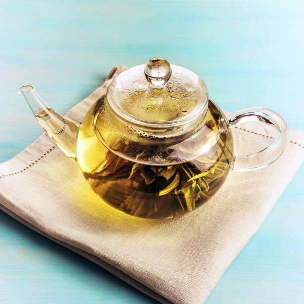 istock Teapot with tea flower on teal background 683763900