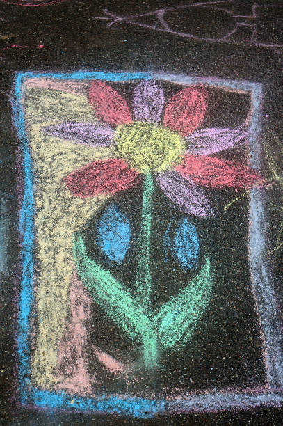 istock Child's crayon drawing of flower on asphalt. 683788284