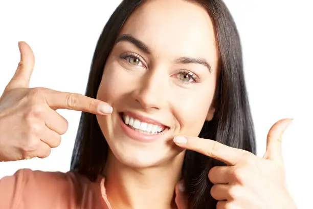 Photo of Woman Pointing To Her Smile With Perfect White Teeth