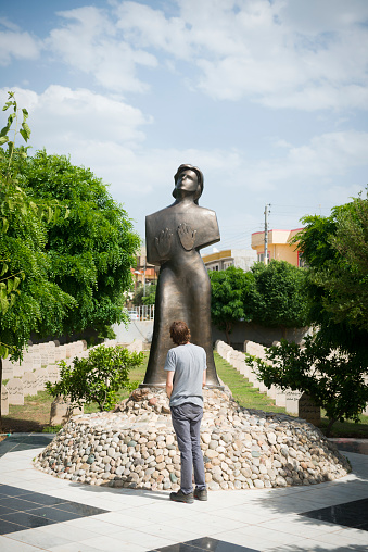 An English visitor to Iraq stands in front of a monument surrounded by graves in a cemetery in Halabja, Iraq. The cemetery holds the remains of the people killed on March 16, 1988, in a gas attack by Sadaam Hussein's forces. The attack occured in the final months of the eight-year-long Iran-Iraq War, and took the lives of up to 5,000 people in Halabja.