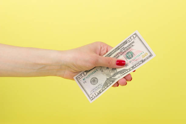 istock American dollars in the woman's hand, yellow background 683805472