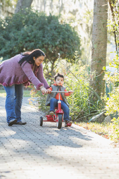 istock Mother and little boy riding tricycle in park 683821164