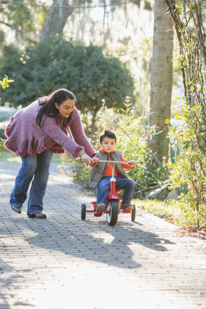 istock Mother and little boy riding tricycle in park 683821192