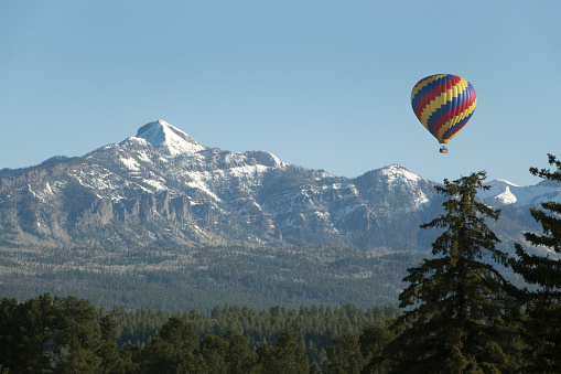 In the San Juan Range, a colorful hot air balloon floats over Pagosa Springs with the Pagosa Peak at an elevation of 12,640 feet  in the background.