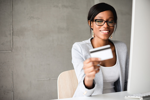 Young african american businesswoman holding a credit card and shopping online.