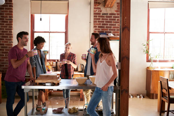 Friends talking over coffee in kitchen, three quarter length