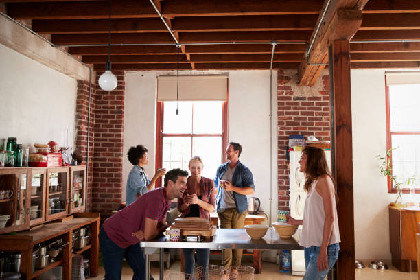 istock Five friends stand talking over coffee in a kitchen 683841336
