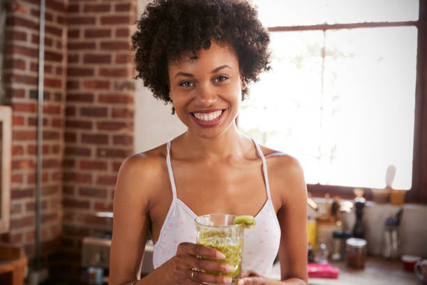 happy mixed race woman holding smoothie, looking to camera - one woman only young women people nightie imagens e fotografias de stock