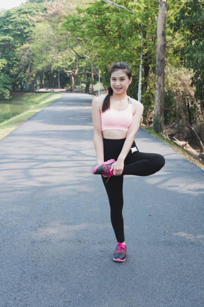 istock Female sport fitness runner getting ready for jogging outdoors on forest path in spring or summer. Healthy young asian woman stretching before running or after exercise in park. 683847272