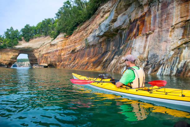 Pictured Rocks Kayaker Arch 2 sea kayaker headed towards an arched rock along the Pictured Rocks National Lakeshore near Munising, Michigan Michigan stock pictures, royalty-free photos & images