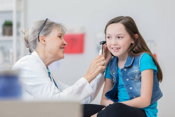 confident pediatrician uses otoscope to check young patient's ear - young ears imagens e fotografias de stock