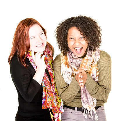 Two excited Black and Caucasian women laughing on white background
