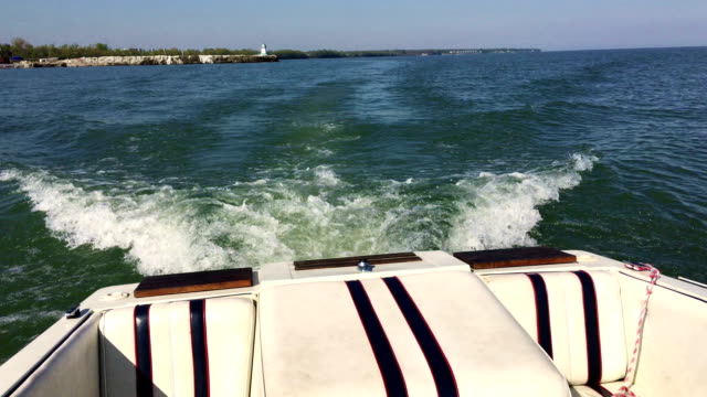 Back of speedboat sailing off into lake erie waters with lighthouse tower in background