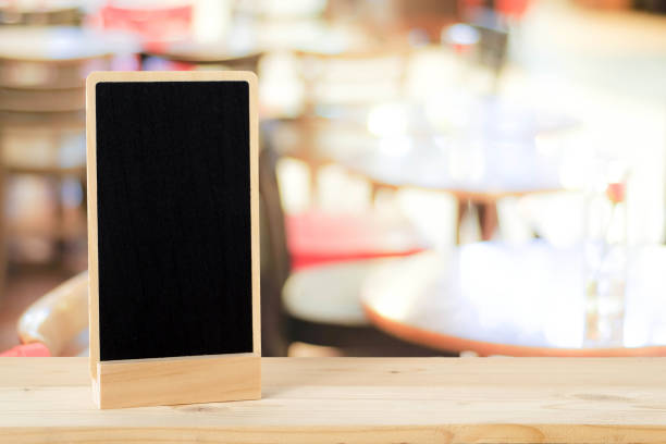 istock Blank chalkboard standing on wood table over blur restaurant with bokeh background, space for text, mock up, product display montage 683885684