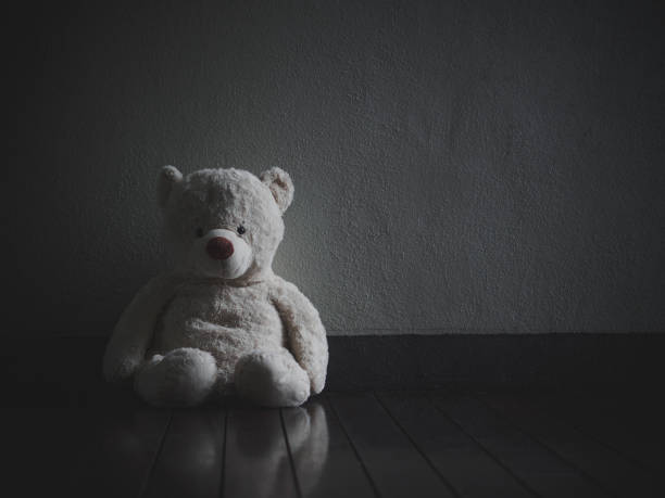 orsacchiotto solitario seduto nella stanza buia (concetto di amore) - teddy bear baby toy stuffed animal foto e immagini stock