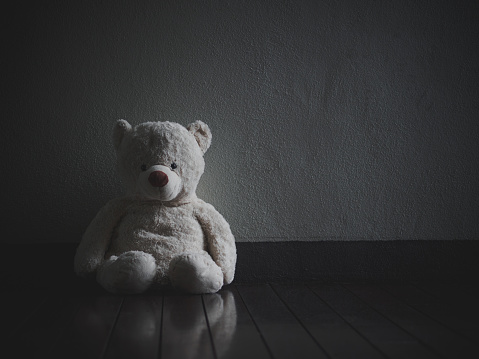 Lonely Teddy Bear Sitting in the dark room (Concept about love)