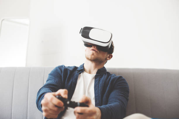 istock Young man playing video game with virtual reality goggles 683892036