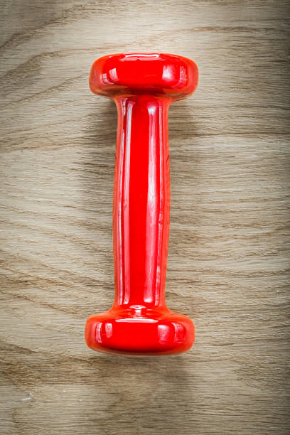 istock Single red dumb-bell on wood board sports training concept 683897576