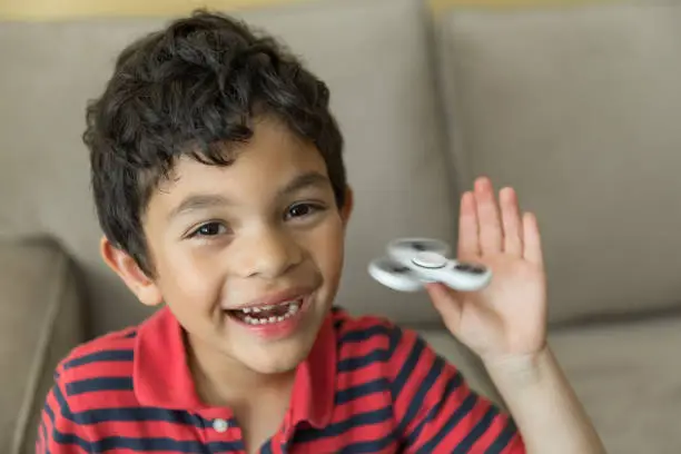 Young handsome, happy boy playing with a fidget spinner