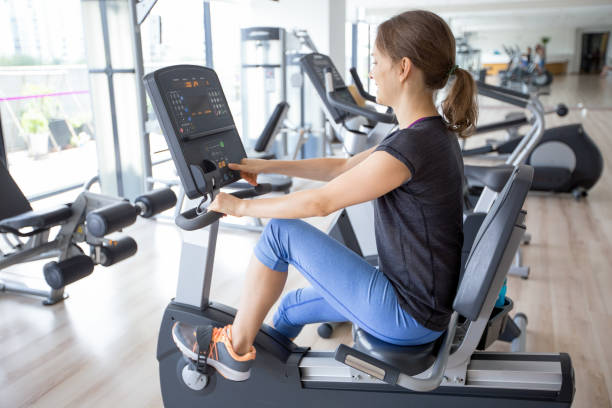 istock Smiling Girl Training on Stationery Bicycle in Gym 683900880