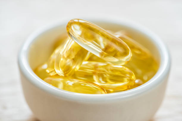 Cod liver oil omega 3 gel capsules in bowl on floor wood Cod liver oil omega 3 gel capsules in bowl on floor wood cod liver oil fish oil vitamin a pill stock pictures, royalty-free photos & images