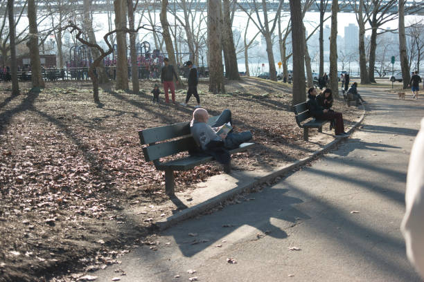 Essen, Germany - August 23, 2015: Distance shot of people sitting on benches on promenade in Essen Kettwig. Scene is close to Mühlengraben behind trees. Area  between Ruhr and historical center.