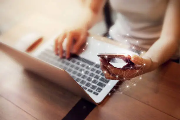 Photo of Woman hand using mobile phone and laptop, Worldwide connection technology interface.