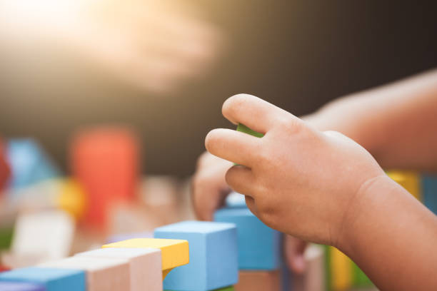 istock Focus on child's hand  playing with colorful wooden blocks 683908232