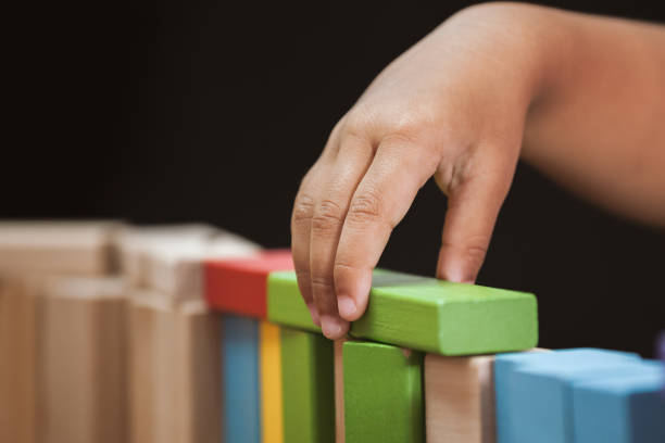 Focus on child's hand  playing with colorful wooden blocks in vintage color tone