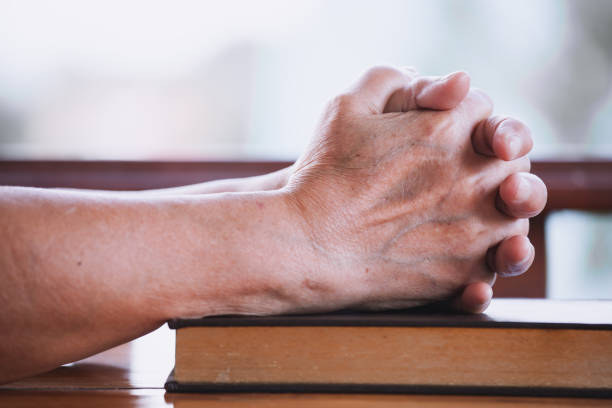 istock Elder woman hands folded in prayer on a Holy Bible 683912366