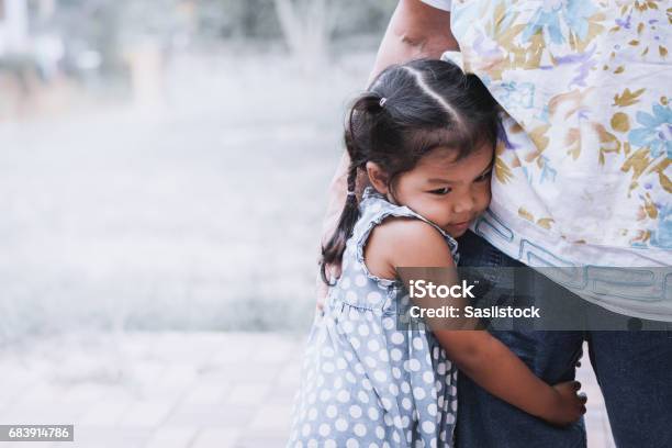 Triste Niña Asiática Abraza La Pierna De La Madre Foto de stock y más banco de imágenes de Niño - Niño, Ansiedad, Miedo