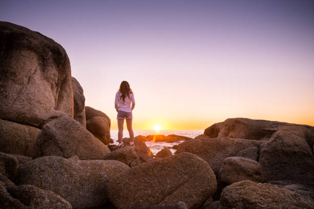 istock Woman standing on rocks at Cape Town beach watching sunset 683922478