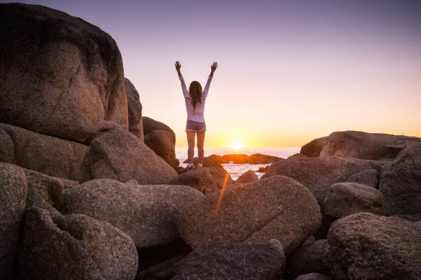istock Woman standing on rocks at Cape Town beach watching sunset 683922504
