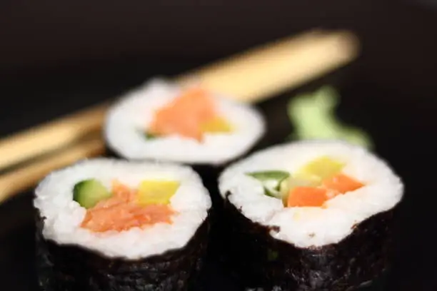 Sushi futomaki with smoked salmon on black plate