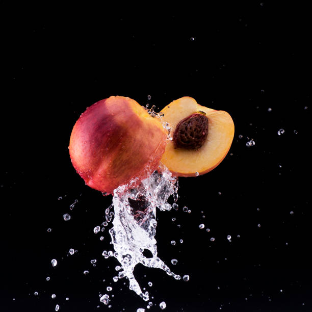 peach and half in water splash on black background