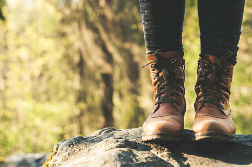 Female legs shod in Hiking boots on the forest background. Travel concept