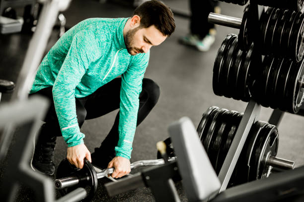 istock Handsome young man uses dumbbells in gym 683948356