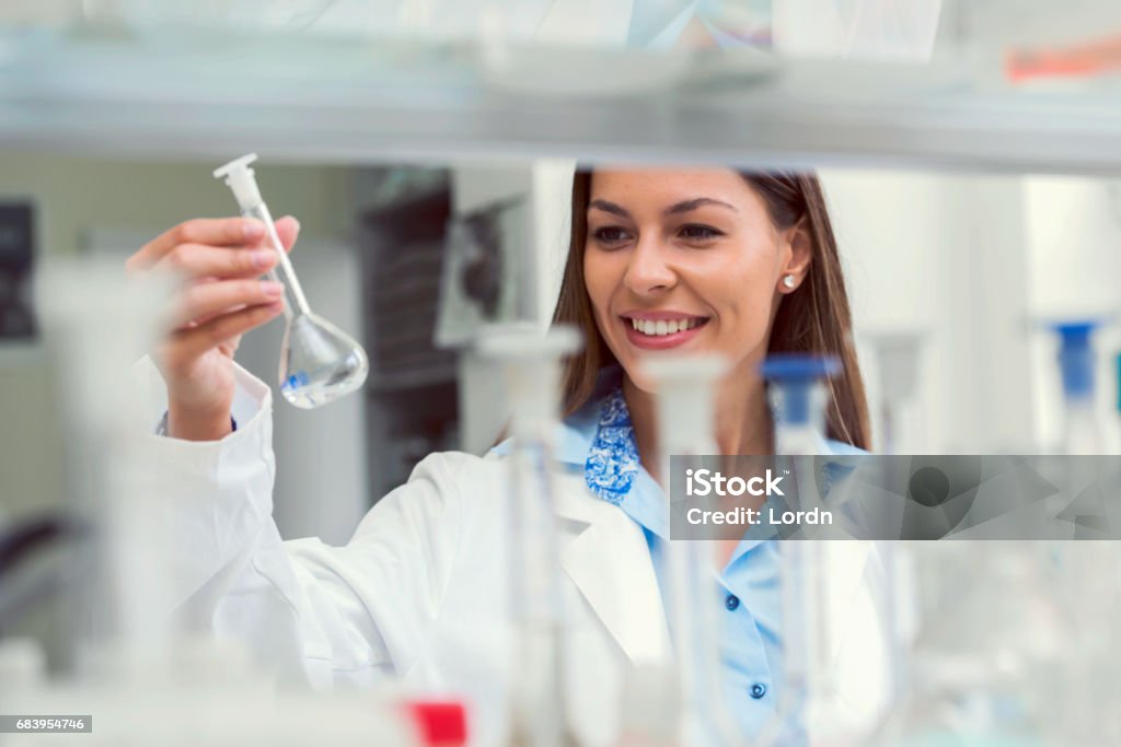 Woman scientist studying chemical liquid in lab flask. Scientist carrying out experiment in research laboratory Woman scientist carrying out experiment in research laboratory Adult Stock Photo