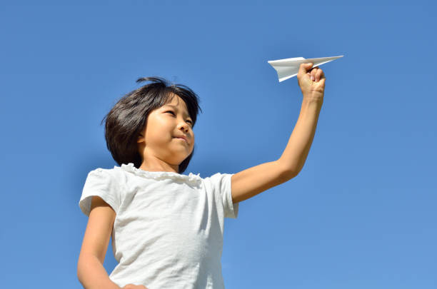 istock Girl flying paper plane into blue sky 683963324