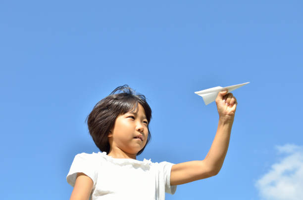 istock Girl flying paper plane into blue sky 683963854