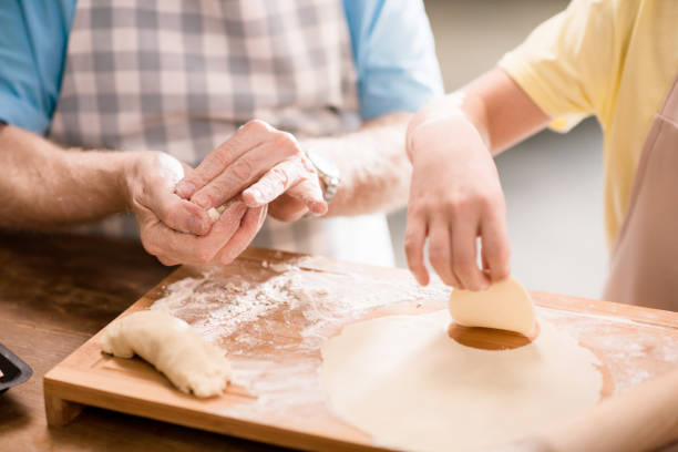 grandchild and grandfather cooking and making dough for cookies with kitchen utensils at kitchen table, cooking in kitchen concept