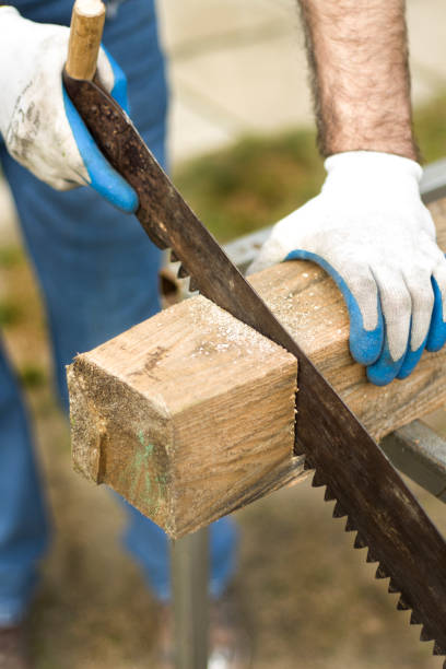 istock Construction worker cuts a hand saw on a piece of raw wood. 683977378