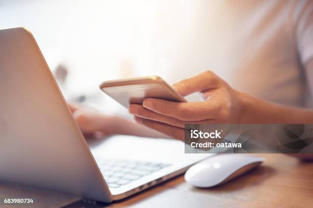 Female Using Smart Phone And Notebook Laptop Computer Stock Photo - Download Image Now