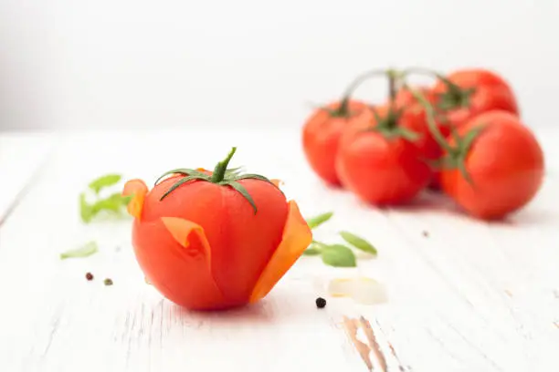 Tomato with purified skin and a bunch of tomatoes on white background. Background image.