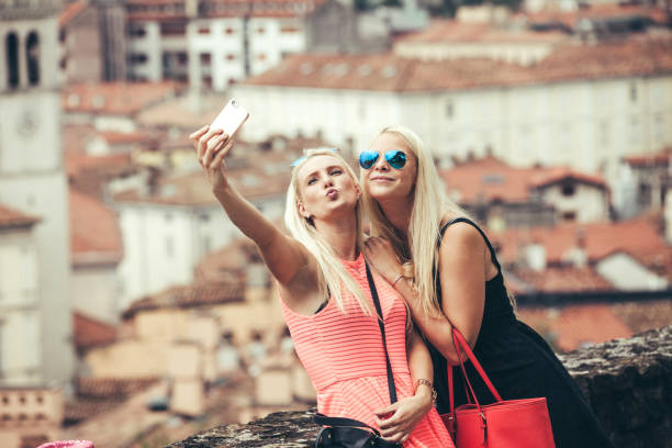 istock Two Young WomanTaking Selfie From Mobile Phone Against City 684001926