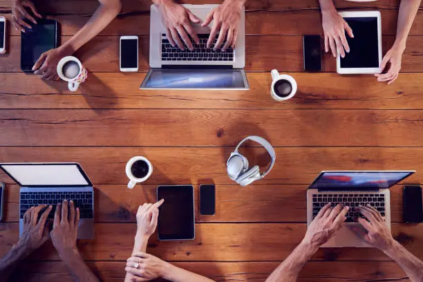 Photo of Overhead shot of young adults using technology at a table