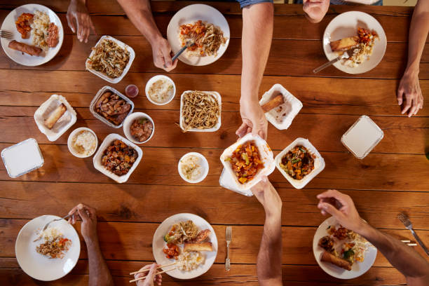 Friends at a table sharing Chinese take-away, overhead view Friends at a table sharing Chinese take-away, overhead view chinese takeout stock pictures, royalty-free photos & images